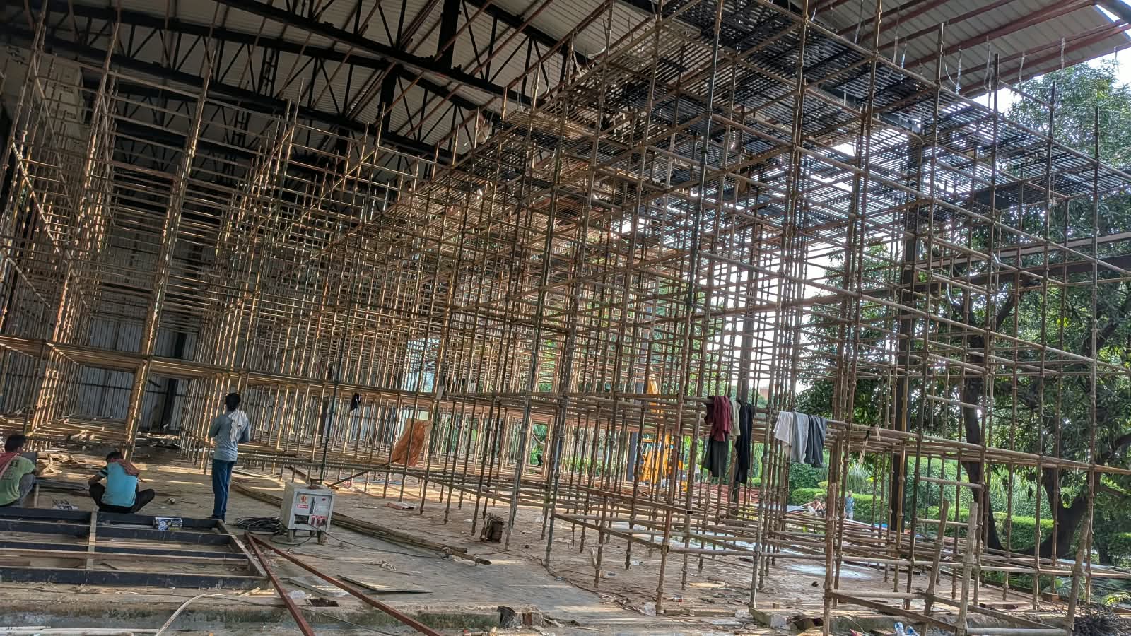 Extensive bamboo scaffolding grid inside a large warehouse under construction