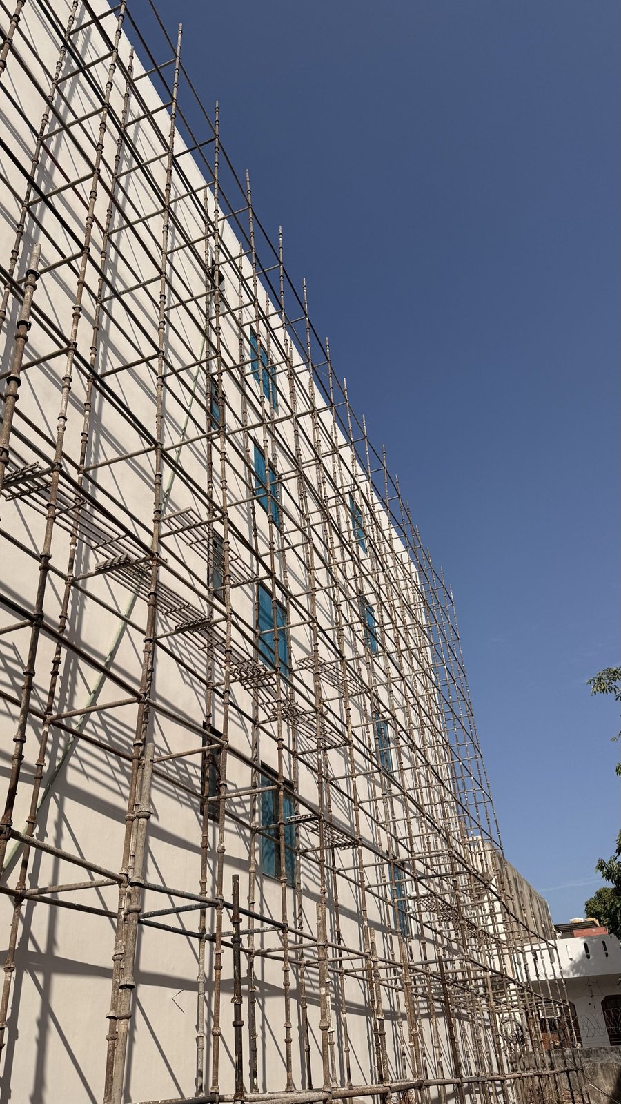 Cuplock scaffolding covering full building facade against clear blue sky